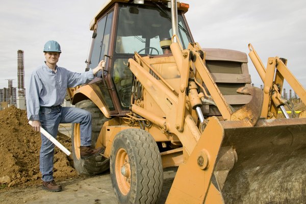 Ingram Publishing/Ingram Publishing/Getty Images Portrait of a construction worker standing beside a bulldozer